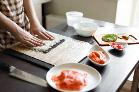 Young teenage boy making maki sushi at homeの写真素材
