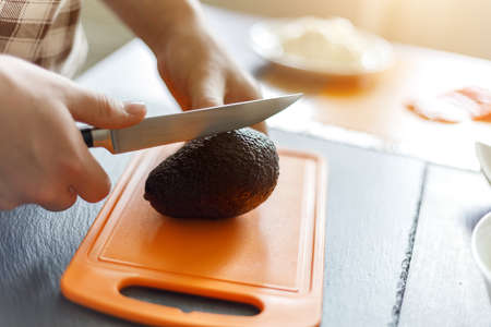 Young boy cutting avocado preparing sushi at home