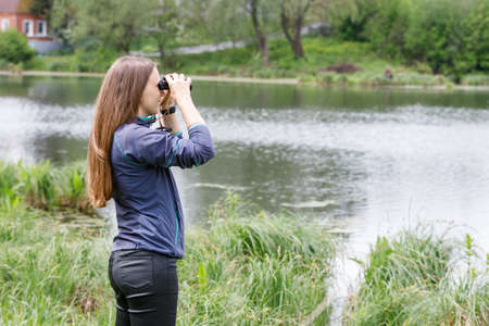 Woman birdwatcher looking for the bird on the lakeの写真素材