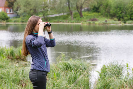 Woman birdwatcher looking for the bird on the lakeの写真素材