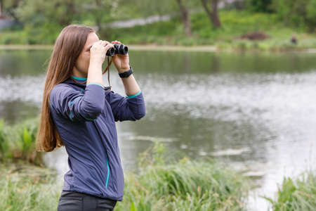 Woman birdwatcher looking for the bird on the lakeの写真素材