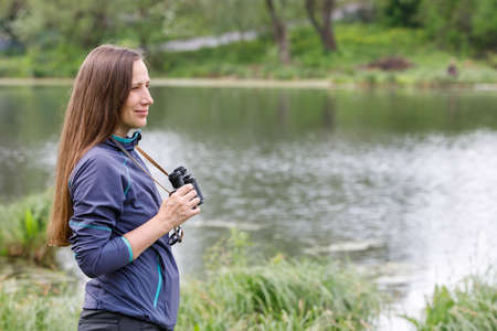 Woman birdwatcher looking for the bird on the lakeの写真素材