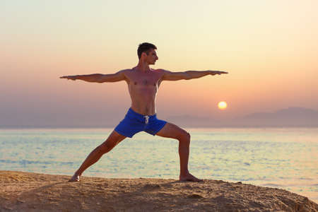 Young man practicing yoga at the seashoreの写真素材