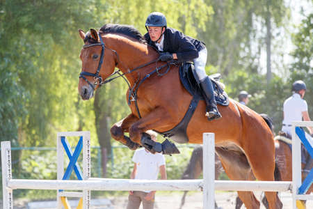 Young rider man jumping over the barrierの写真素材