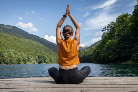 Young woman meditating or practicing yoga at the lake in the mountains.の写真素材