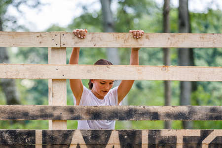 Young sportswoman climbing timber wall on her obstacle race courseの写真素材