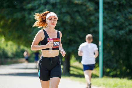 Young sporty woman running marathon in the park.の写真素材