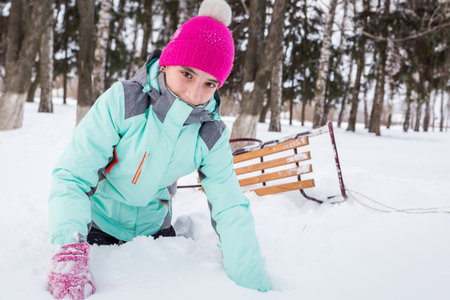 Teengae girl having fun playing with the sledge in the snow in winterの写真素材