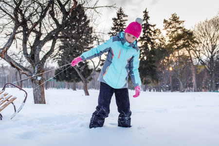 Teengae girl having fun playing with the sledge in the snow in winterの写真素材