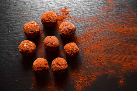Chocolate homemade candy truffles laying on the black slate background. Homemade cooking background with copy spaceの写真素材