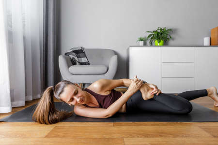 Young yogi woman practicing yoga at home. Fitness girl stretching legs .の写真素材