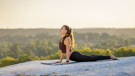 Young fitness woman doing yoga outdoors at sunset.