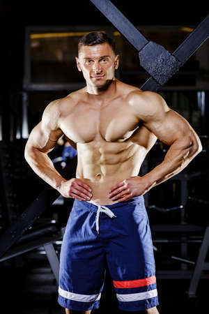 Young bodybuilder with great muscles posing in gymの写真素材