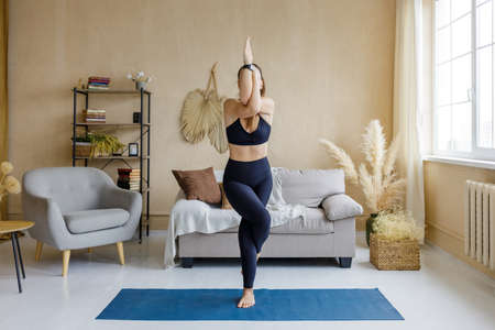 Young sporty woman doing morning yoga practice at home.の写真素材