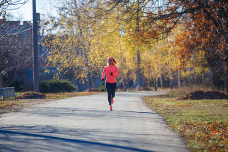 Young fitness woman running on the road in the cold morning in winter.の写真素材