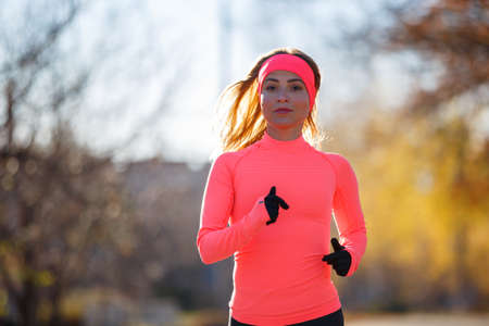 Young fitness woman running on the road in the cold morning in winter.の写真素材