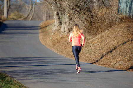 Young fitness woman running on the road in the cold morning in winter.の写真素材