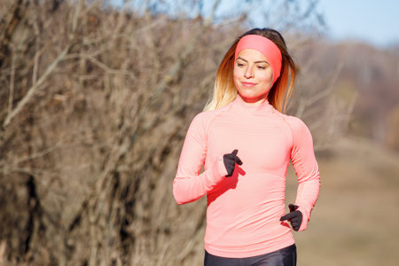 Close up portrait of young running woman in park in frosty morningの写真素材