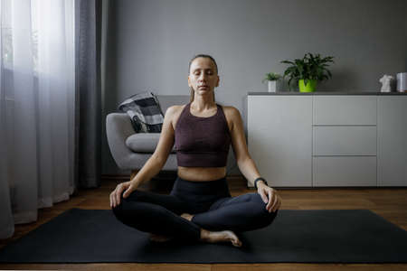 Young woman meditating at home in winterの写真素材