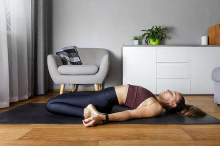 Young yogi woman practicing yoga at home. Heart opening stretching fitness relaxing poseの写真素材