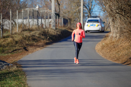 Young fitness woman running on the road in the cold morning in winter.の写真素材