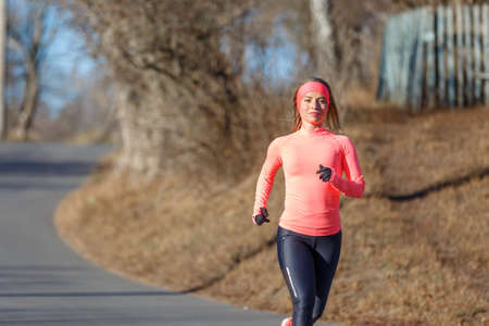 Young fitness woman running on the road in the cold morning in winter.の写真素材
