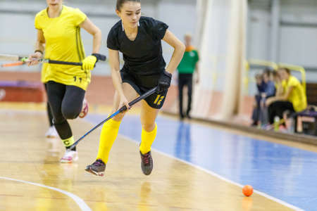Young woman playing indoor hockey and leading the ball in attackの写真素材