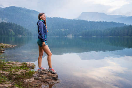 Young woman enjoying view of black lake or Crno jezero in Durmitor nature park, Montenegroの写真素材