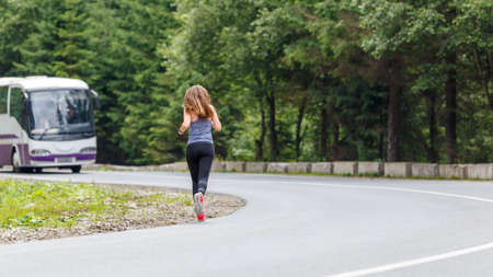 Runner woman running on the mountain road through the forest.の写真素材