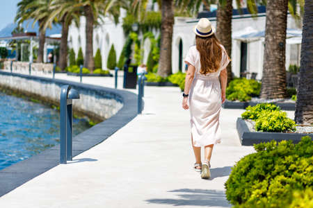 Young lady in dress and hat walking near the marina jettyの写真素材