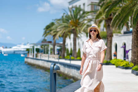 Young lady in dress and hat walking near the marina jettyの写真素材