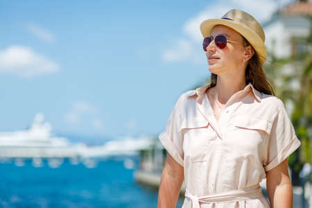 Portrait of young lady in dress and hat walking near the marina pierの写真素材