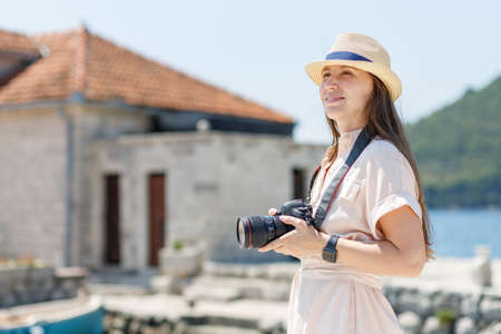 Young travel lady in dress takes photo with professional camera at sunny dayの写真素材
