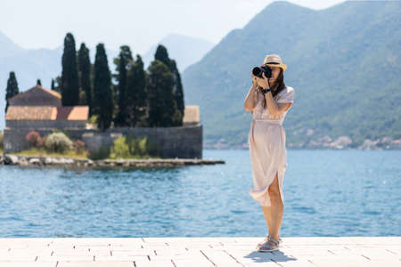 Young travel lady in dress takes photo with professional camera at sunny dayの写真素材