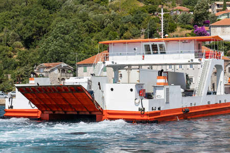 Ferry ship transporting cars and lorries through bay in mediterranean townの写真素材