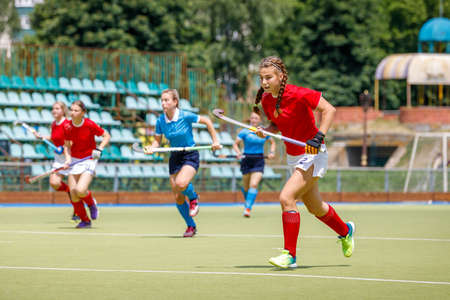 Young women field hockey players running on the pitchの写真素材