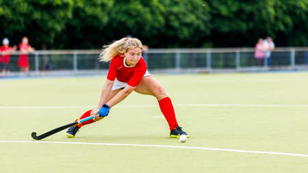 Young woman field hockey player hit the ball in attack on gameの写真素材