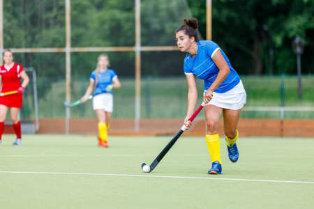 Young woman field hockey player leading the ball in attackの写真素材