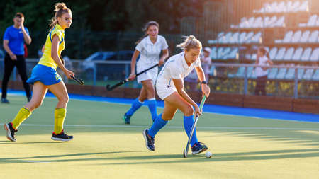 Young girl lead the ball in attack during field hockey gameの写真素材