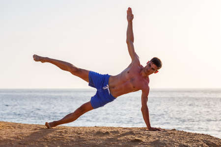 Young man doing yoga practice at the beach in the morningの写真素材
