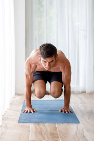 Young man doing strength pilates or yoga workout in the morningの写真素材