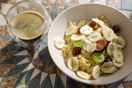 Oatmeal cereal bowl with banana, grapes and the cup of coffee. Top view image of breakfastの写真素材