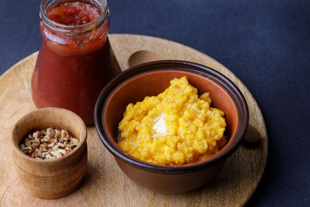 Sweet pumpkin porridge in clay bowl with jam and nutsの写真素材