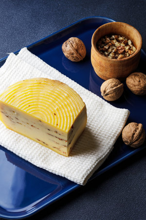 A piece of cheese served with walnuts on the blue tray