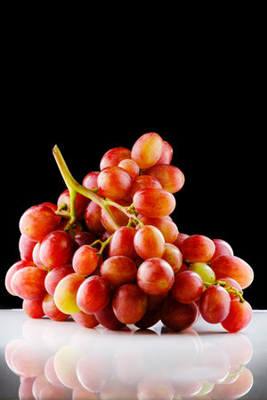 Shiny bunch of ripe red grapes isolated on black and white backgroundの写真素材
