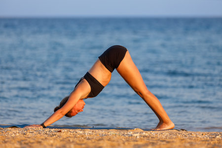 Young woman practicing yoga at the beach in the morningの写真素材