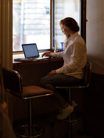 Young freelance woman in white shirt working with laptop in cafeの写真素材