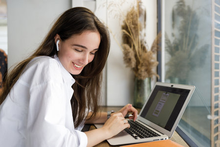 Young woman in white shirt using her laptop for online educationの写真素材