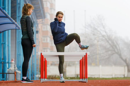 Two young women doing hurdle athletics training on the trackの写真素材