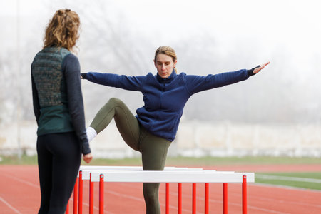 Two young women doing hurdle athletics training on the trackの写真素材